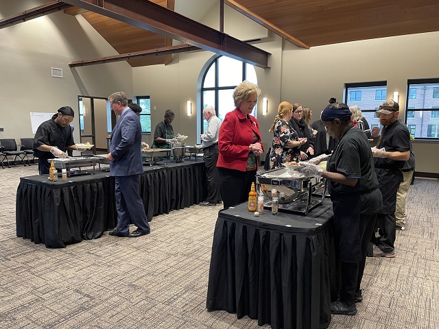 Guests at the Hope and Healing Fundraiser Breakfast Make Their Way Through Buffet-Style Catering Line. Catering Team Serves Food From Behind Tables.