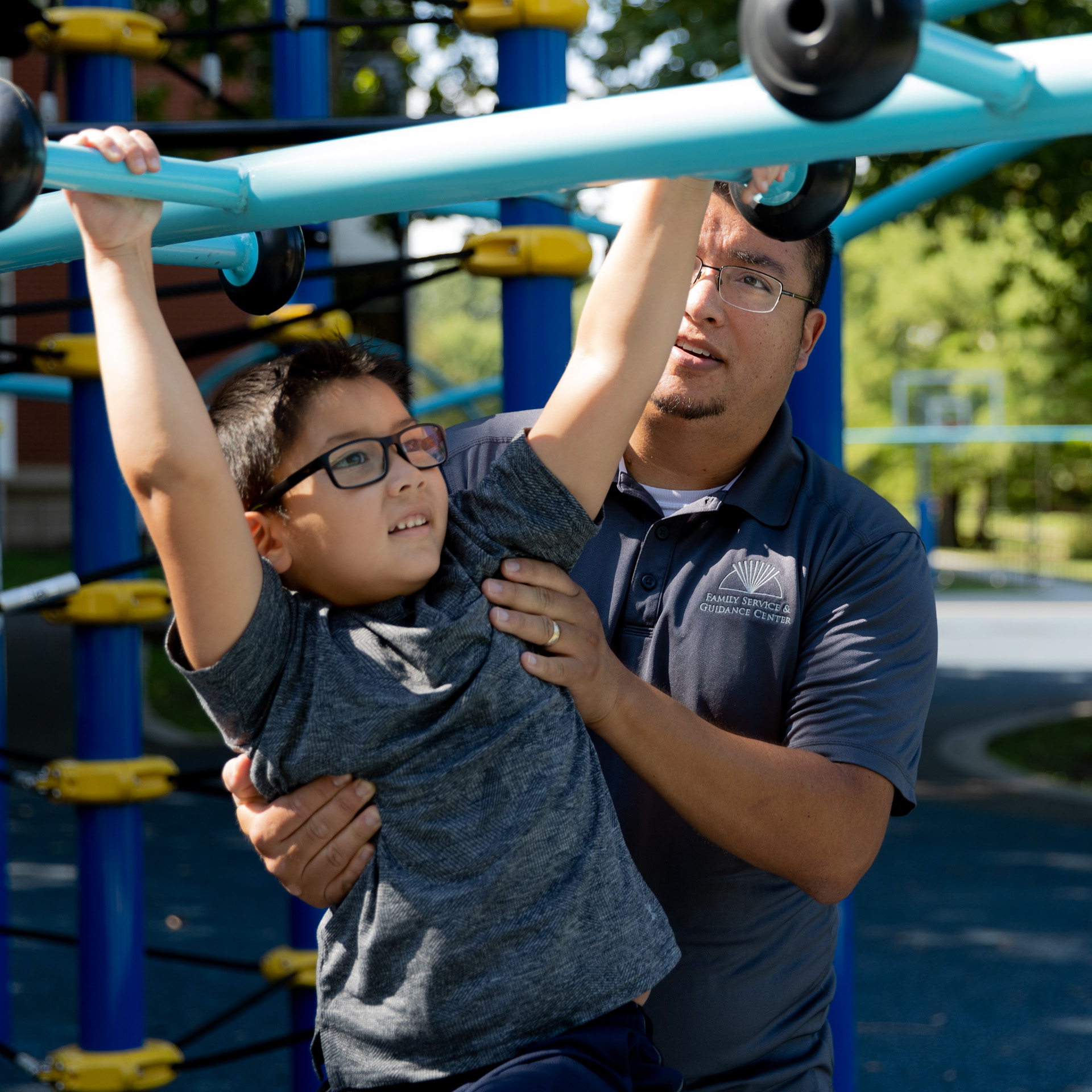 member of staff helping a child across the monkey bars