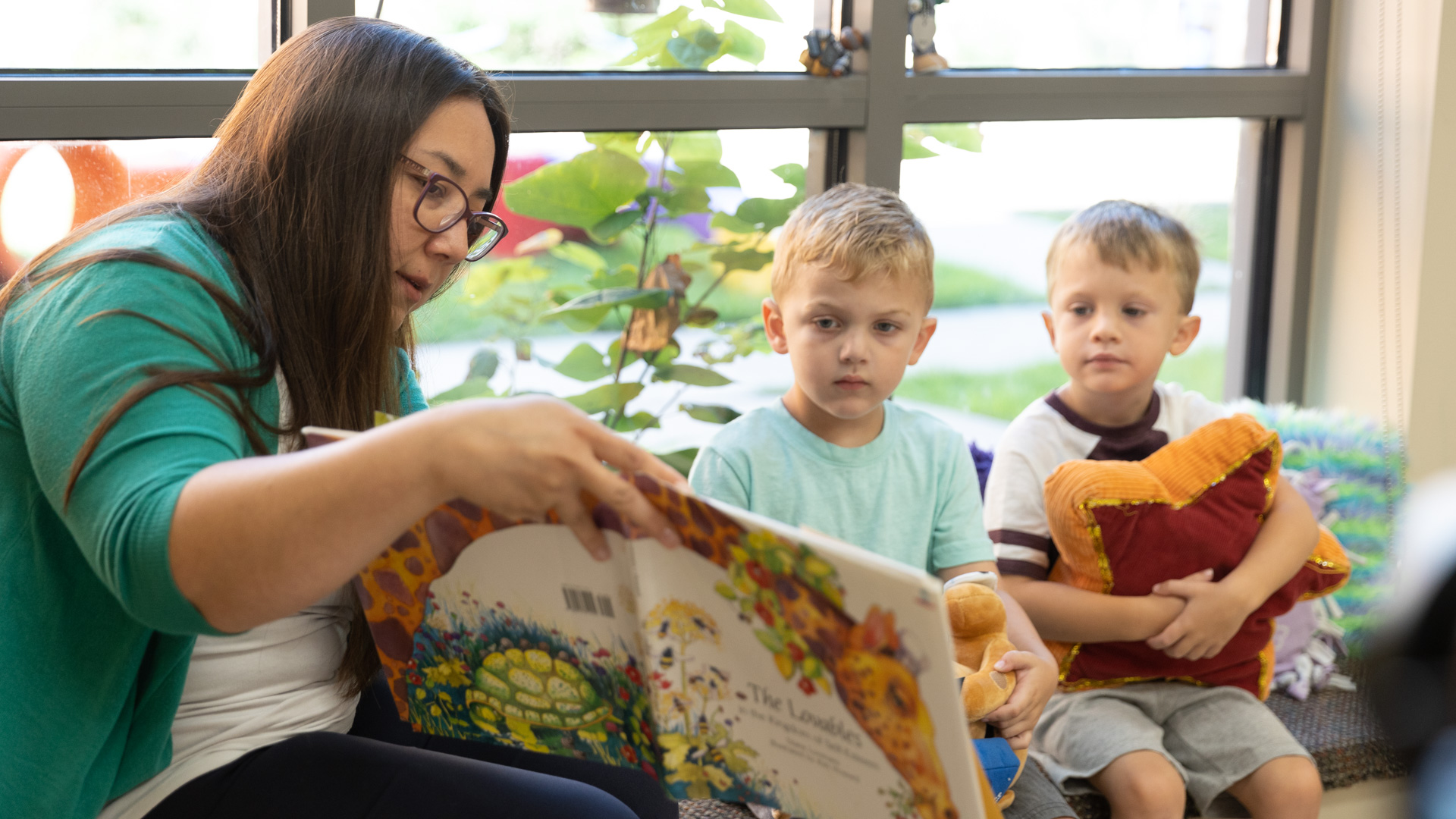 Member of staff reading picture book to two kids
