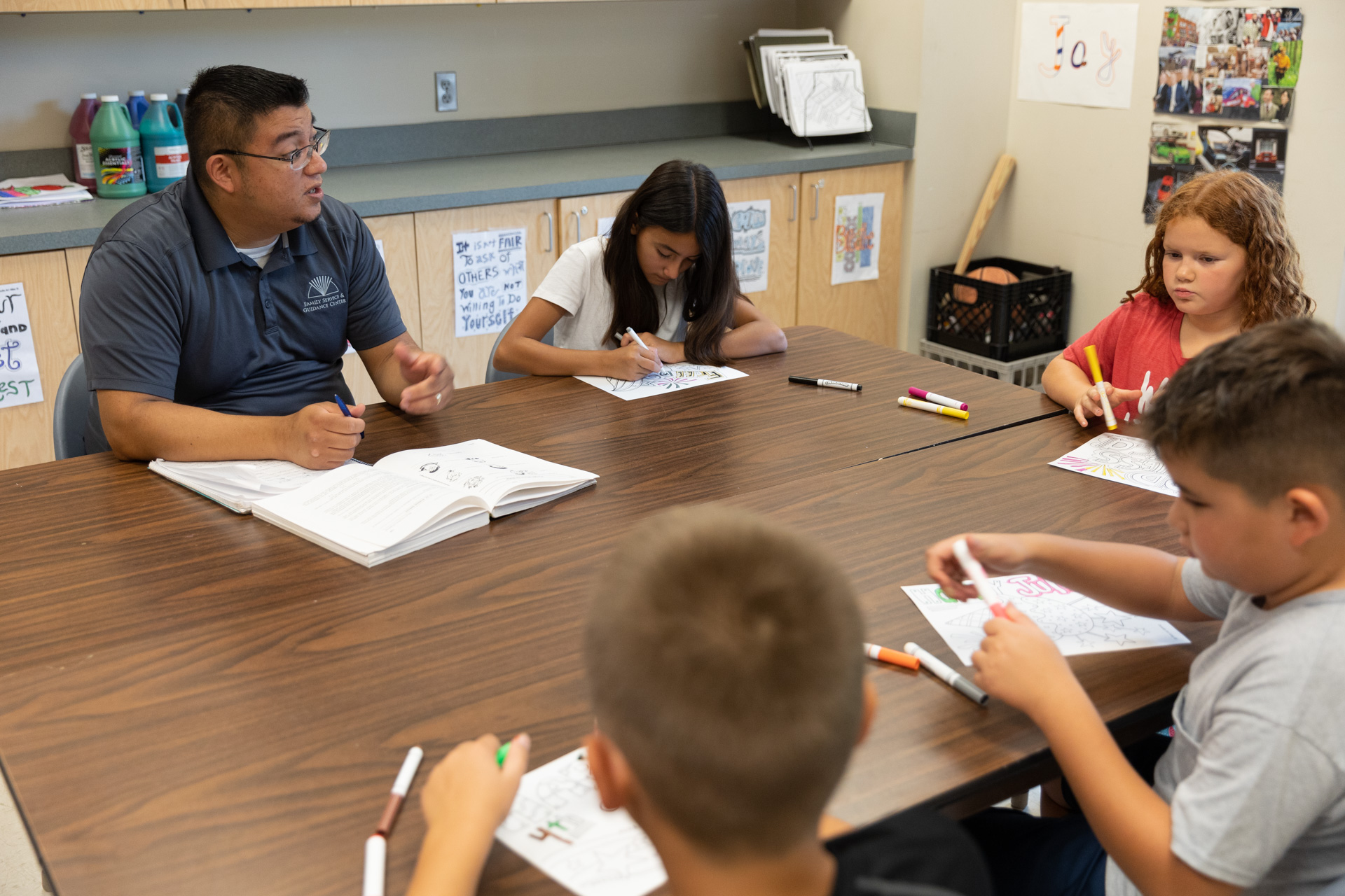 member of staff teaching a lesson with kids at a table