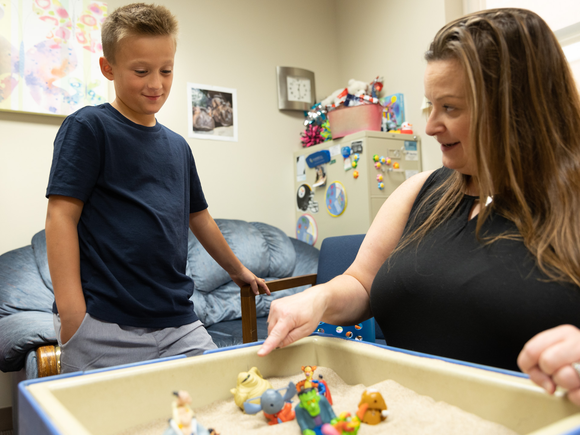 female member of staff playing in the sandbox with a student