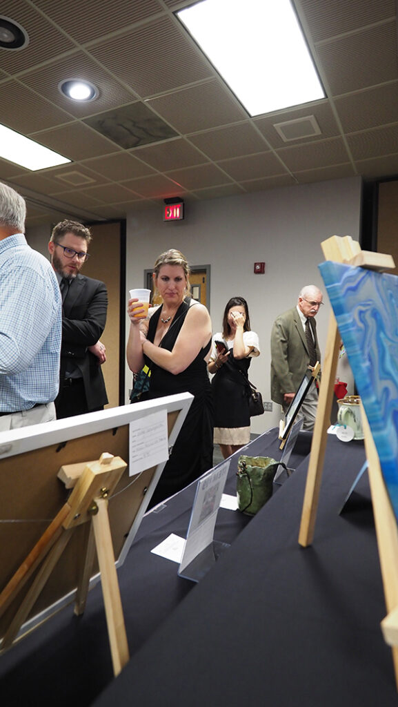 The silent auction room is filled with people looking at items displaced on tables.