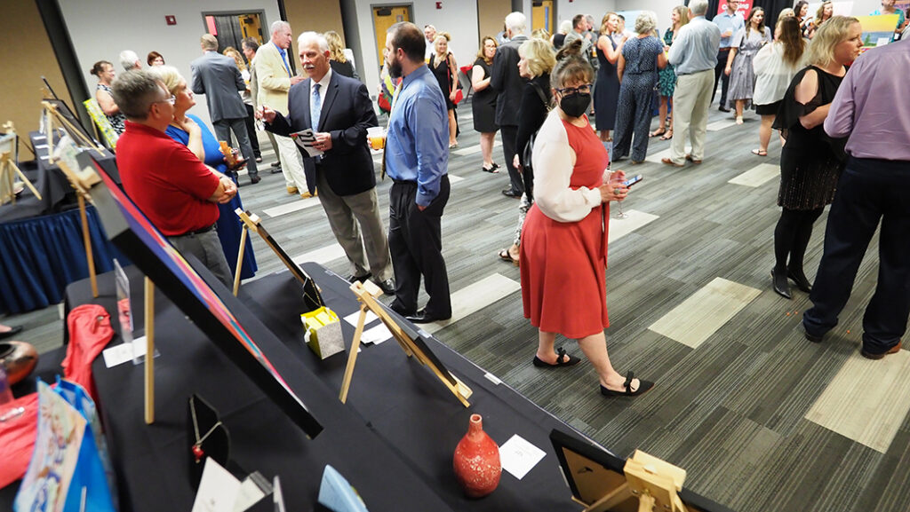 The silent auction room is filled with people looking at items displaced on tables.