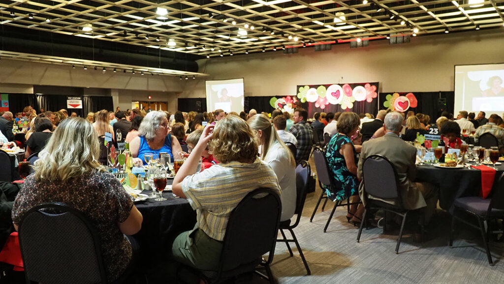 A group of guests sitting at tables looking towards the stage.