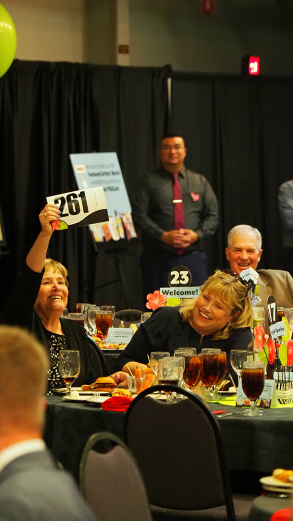 A female guest displays her bidder number while bidding in the live auction.